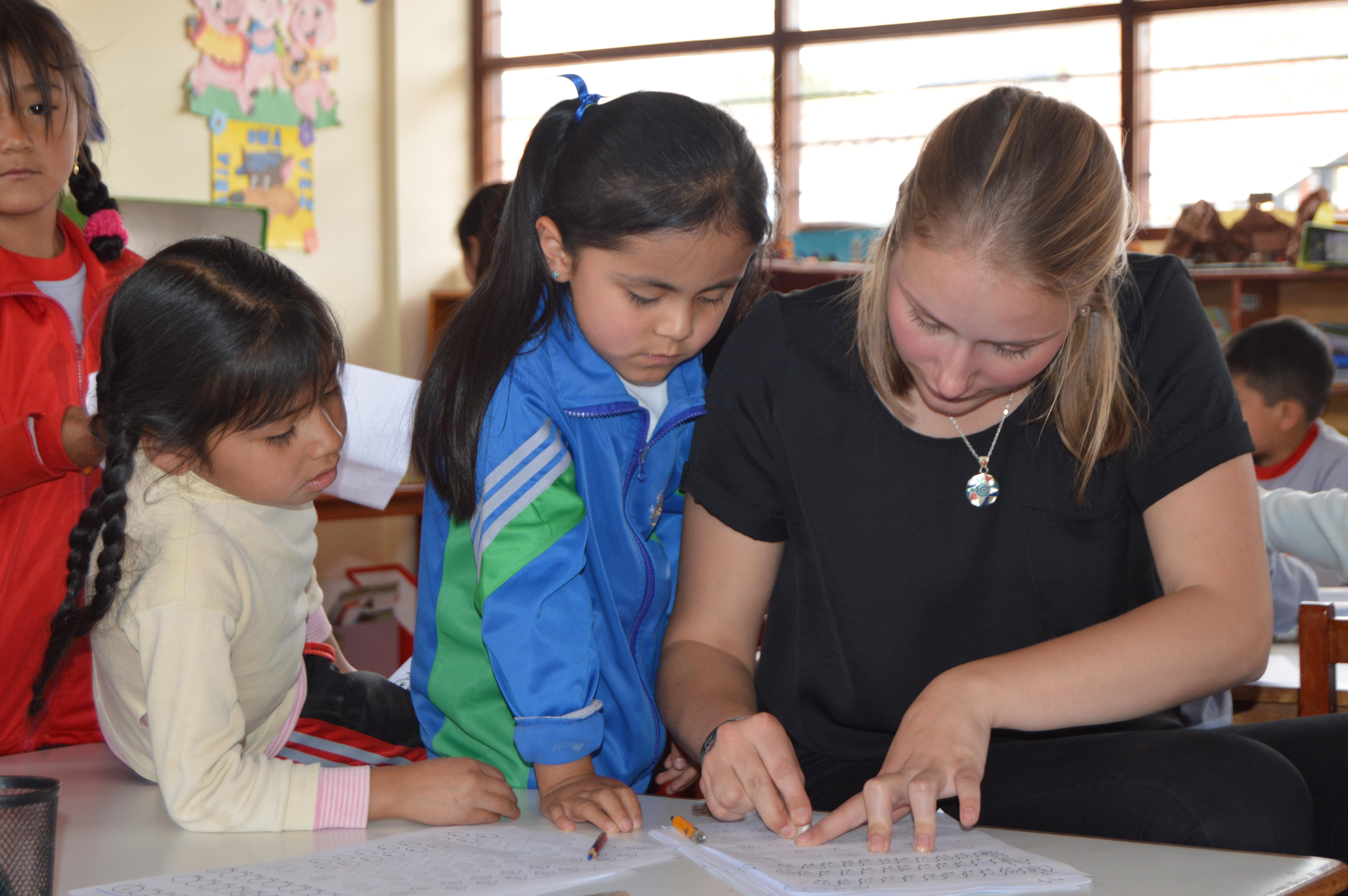A Projects Abroad volunteer corrects a mistake on one of her students practice test while gaining teaching work experience in Peru Teaching volunteer in Peru explains to her student where she went wrong in her work and how to correct it